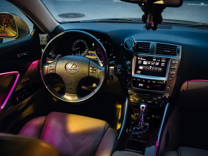 Car interior at dusk with pink accent light strips on the doors and dash