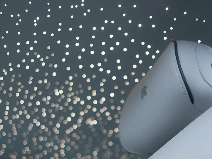 Car roof lined with tiny points of light over white leather seats
