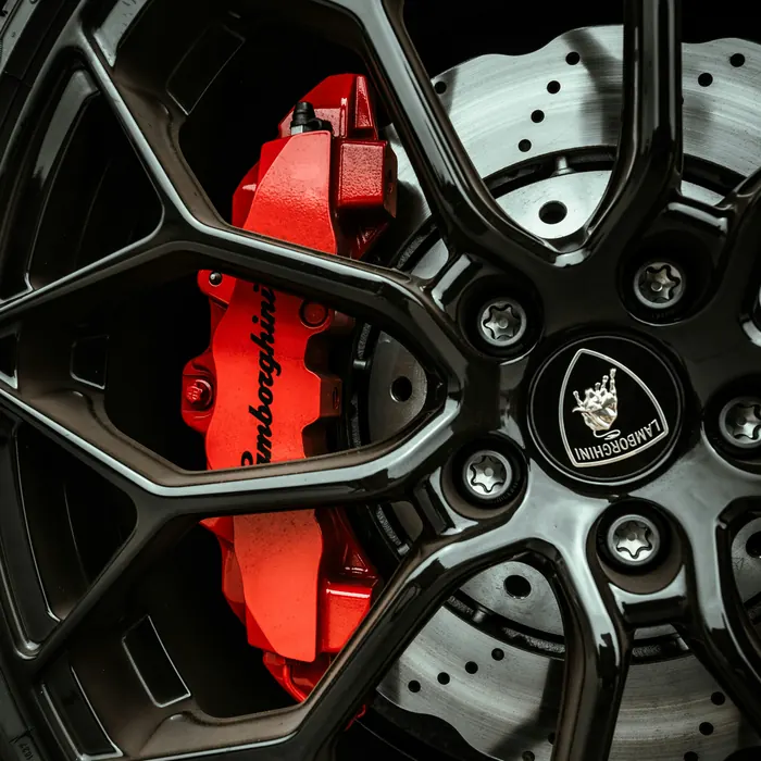 Glossy red brake caliper behind a black wheel