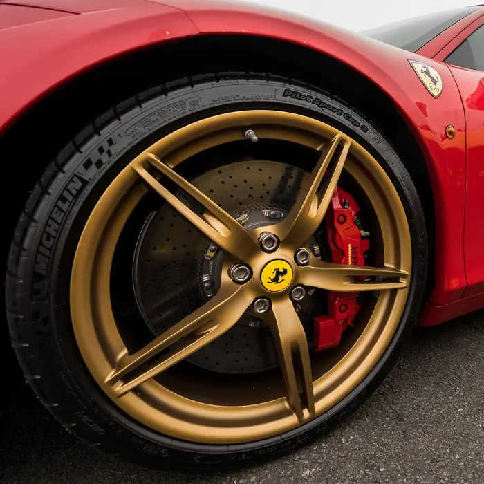 Bronze five-spoke wheel with a red caliper on a red sports car