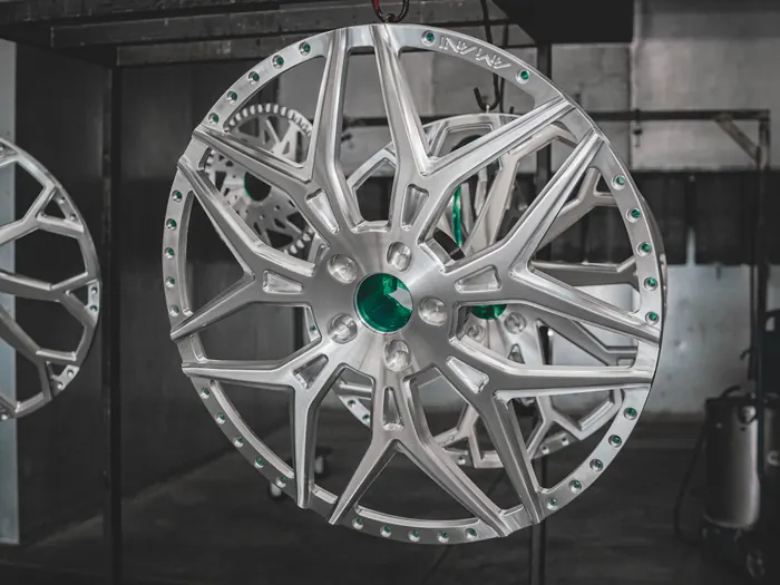 Powder coated wheel faces hanging on a rack after curing